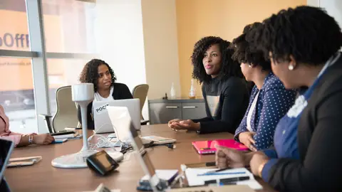 Diverse team of professionals engaging in a collaborative office meeting around a desk.