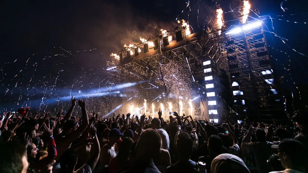 Vibrant concert scene with crowd enjoying night festival and dynamic stage fireworks.