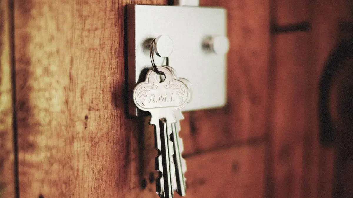 Detailed shot of keys hanging in a door lock on a wooden surface, warm tones.