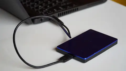 External hard drive connected to a laptop, showcasing portable storage solution.