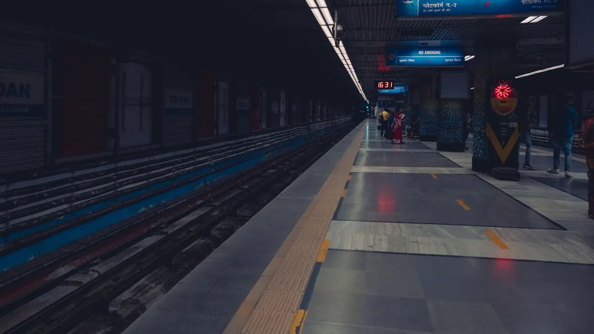 A dimly lit metro station platform with passengers waiting, showcasing urban public transportation.