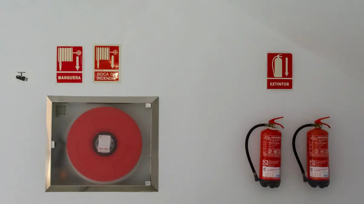 Fire safety setup with extinguishers and hose reel on a white wall for emergency preparedness.