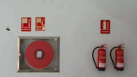 Fire safety setup with extinguishers and hose reel on a white wall for emergency preparedness.