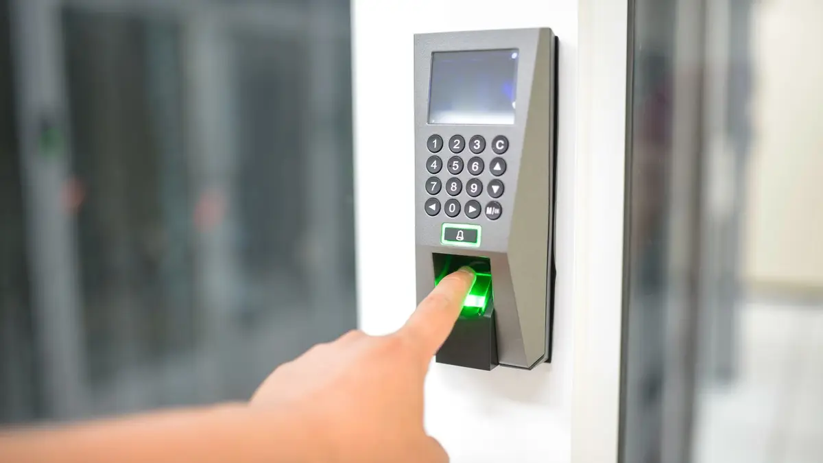 A person uses a fingerprint scanner for secure entry in a business setting.