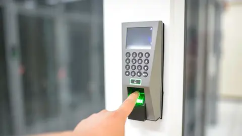 A person uses a fingerprint scanner for secure entry in a business setting.