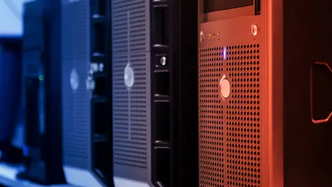 Close-up of tower servers in a data center with blue and red lighting.