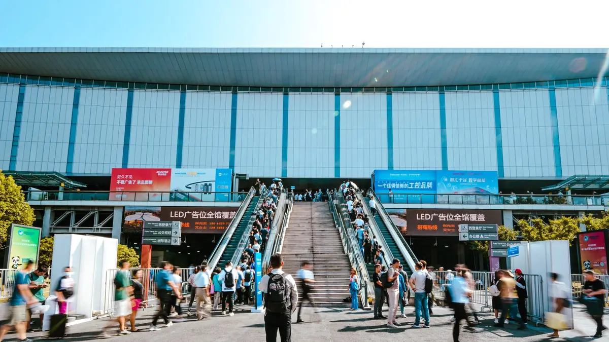 People entering Shanghai exhibition center via outdoor escalator during daytime.