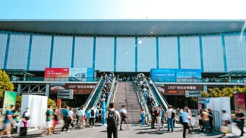 People entering Shanghai exhibition center via outdoor escalator during daytime.