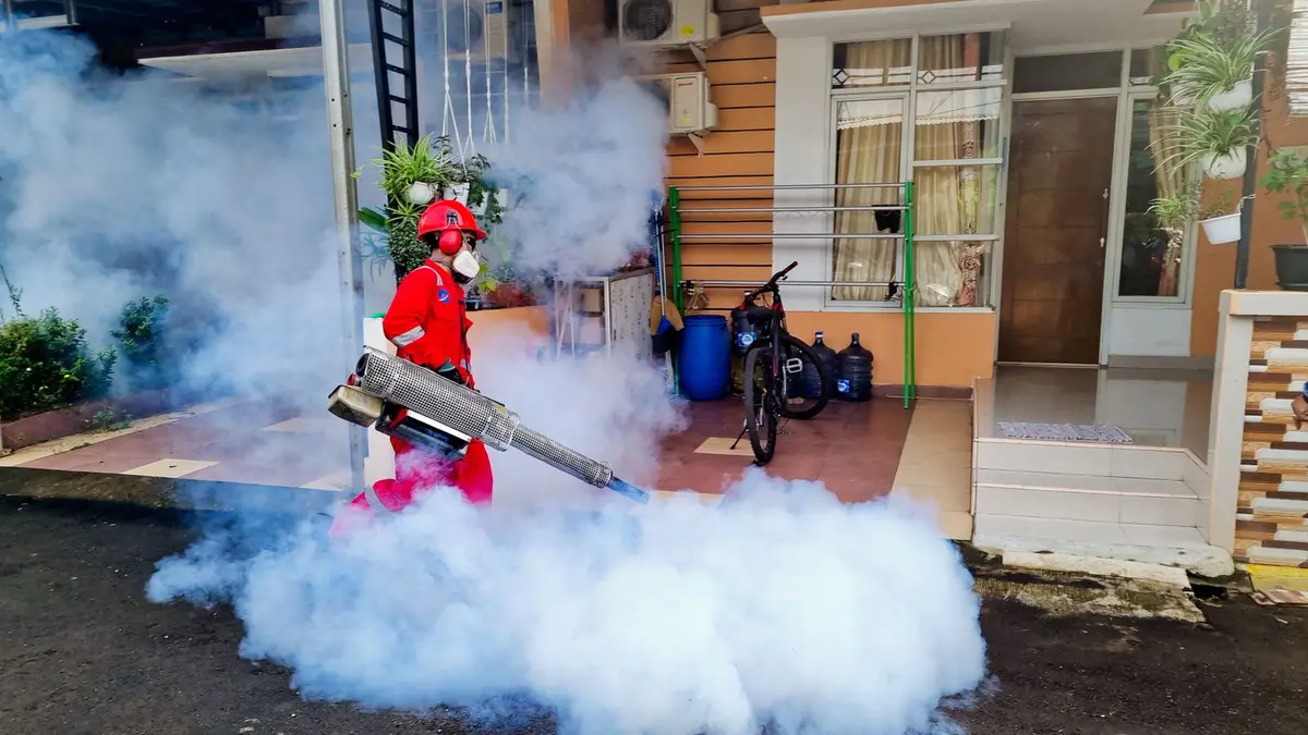 Pest control specialist using a smoke machine to fumigate outside a house.