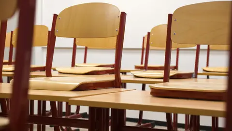 A modern and empty classroom featuring wooden chairs and desks with a focus on education and learning spaces.