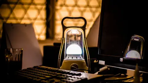 A tranquil night workspace in Indonesia lit by a lantern's glow.