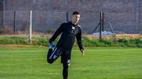 A football player stretching outdoors on the field during training for improved performance.