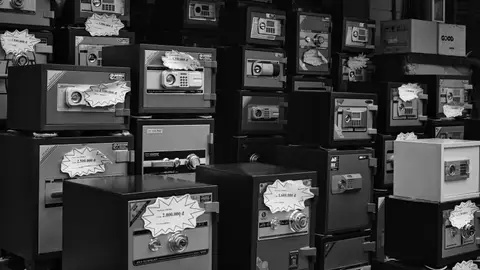 Monochrome photo of stacked safes with price tags in a store setting.