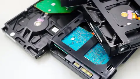 Stack of internal hard disk drives for digital storage on white background.