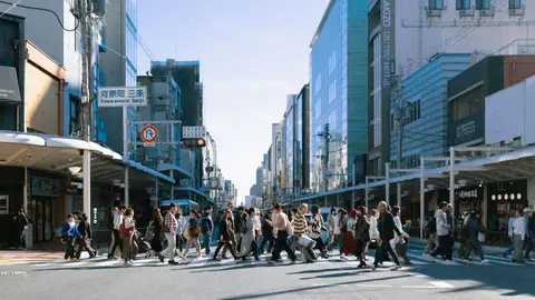 Pedestrians cross the street in the bustling Kawaramachi Sanjo area during the day.