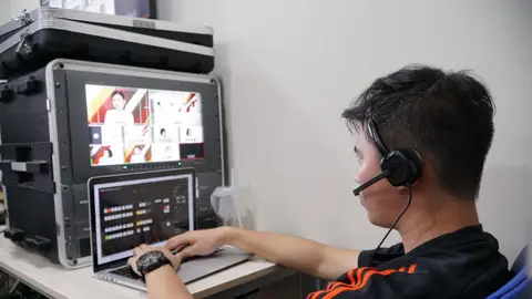 Technician manages multiple video feeds using laptop and monitor in studio setting.