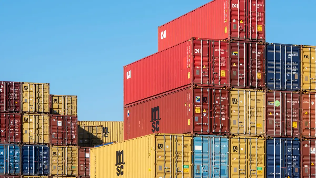 A vibrant collection of stacked shipping containers under a clear, blue sky. Ideal for logistic themes.