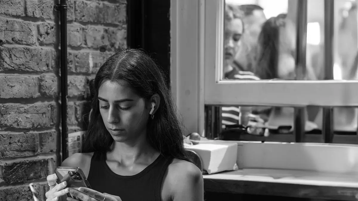 A young woman focused on her smartphone indoors, expressing modern lifestyle.