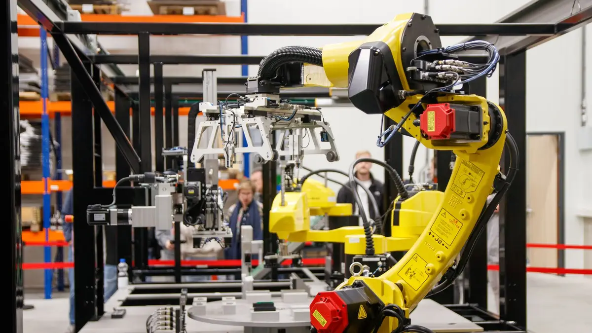 Close-up of a yellow industrial robotic arm in action at a modern manufacturing facility.