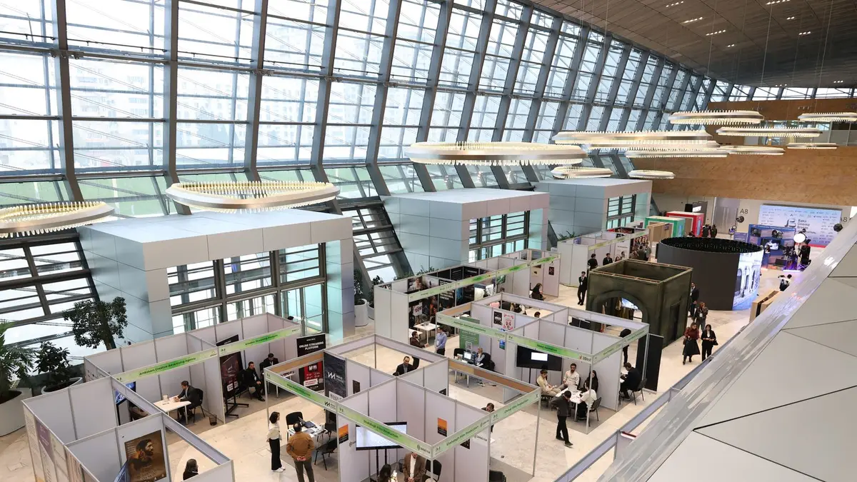 A bustling trade show exhibition inside a modern hall with people networking and exploring booths.