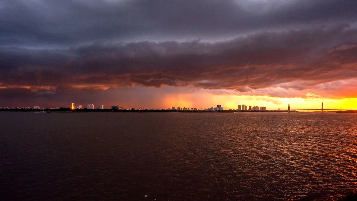 A city skyline under a dramatic stormy sky with a vibrant sunset provides a powerful contrast.