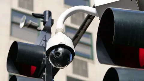 Close-up of a modern dome security camera monitoring an urban street.