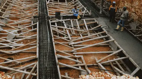 Construction workers at a site with wooden framework in progress, showcasing development.