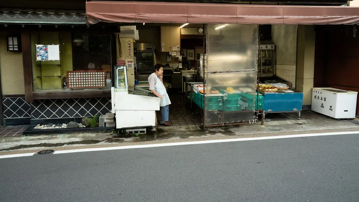 A traditional Kyoto shop with a local vendor standing at the entrance, showcasing Japanese culture.