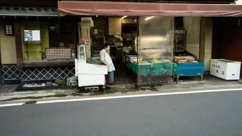 A traditional Kyoto shop with a local vendor standing at the entrance, showcasing Japanese culture.