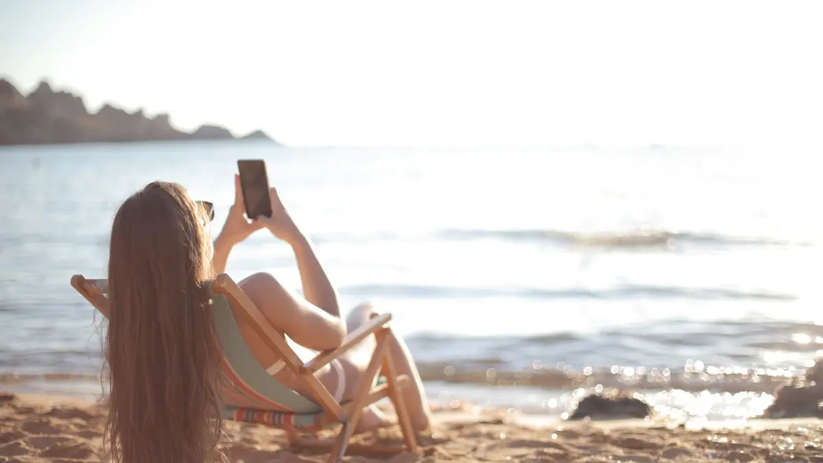 Woman in bikini relaxes on a beach chair by the ocean, capturing summer memories.