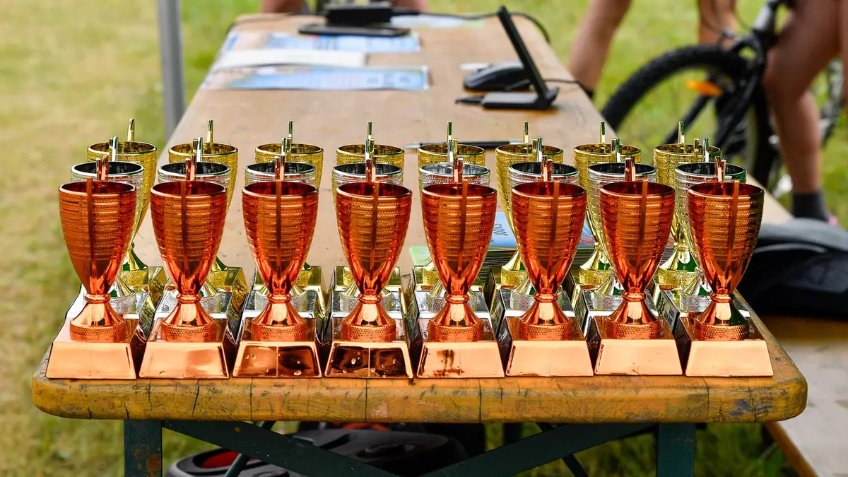 Bronze and gold trophies displayed on a wooden table at an outdoor cycling event in Estonia.
