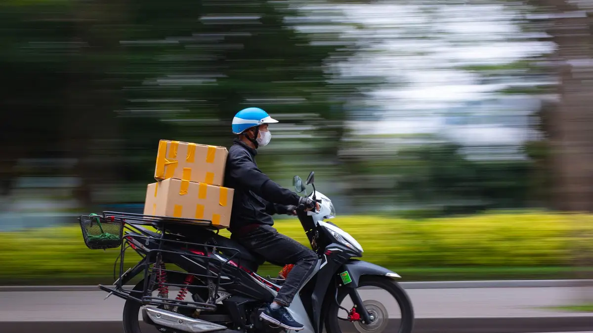 Fast-paced delivery service on a scooter in urban setting, capturing motion and speed.