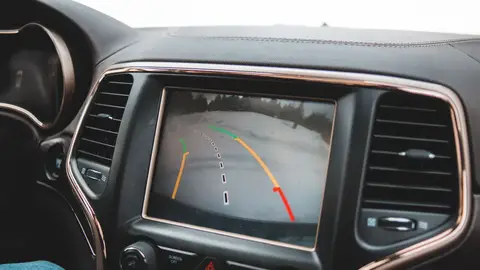 Close-up of a car's dashboard showing a rearview camera display for parking assistance.