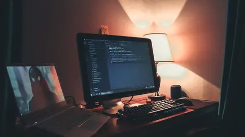 Warmly lit home office with dual screens for coding and programming. Perfect modern workspace for tech enthusiasts.