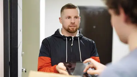 A delivery driver in a hoodie receiving a package indoors, focusing on customer interaction and modern lifestyle.