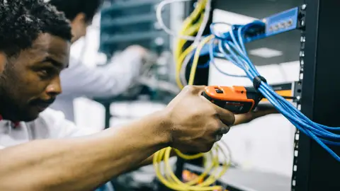 Side view crop concentrated African American engineer repairing equipment by using electric screwdriver
