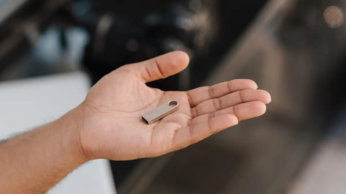From above of crop anonymous male demonstrating modern portable memory device on palm of hand
