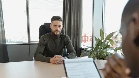 Professional man in turtleneck at office desk during an interview.