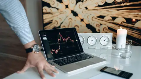 A contemporary desk setting with technology gadgets and a laptop displaying a stock chart.