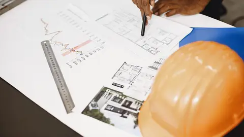 Architect analyzing building blueprints with tools on a desk, showcasing planning and design.