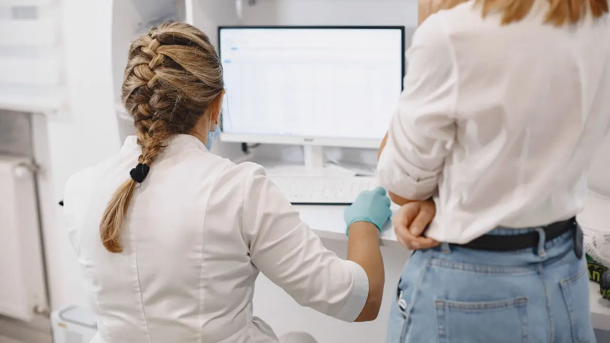Two healthcare professionals working on a computer in a hospital setting, focused on data analysis.