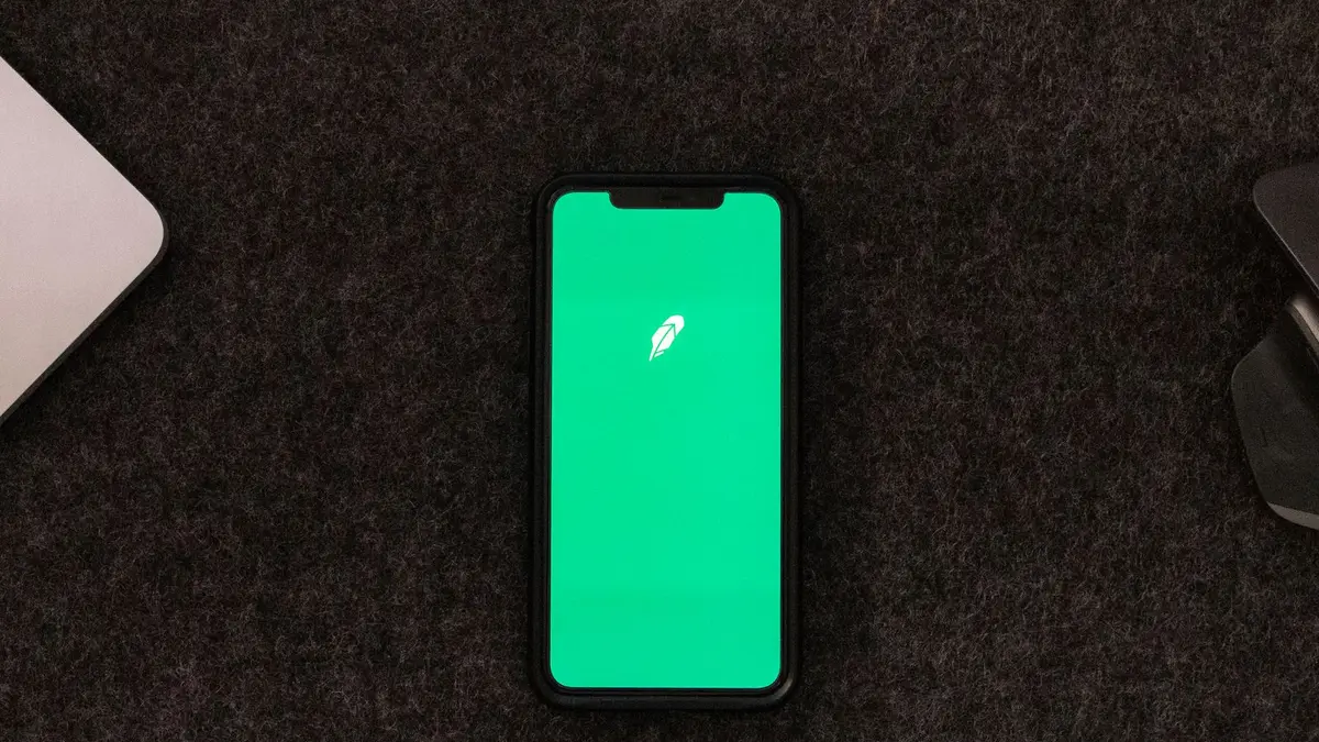 Smartphone displaying trading app on a desk for stock finance concepts.