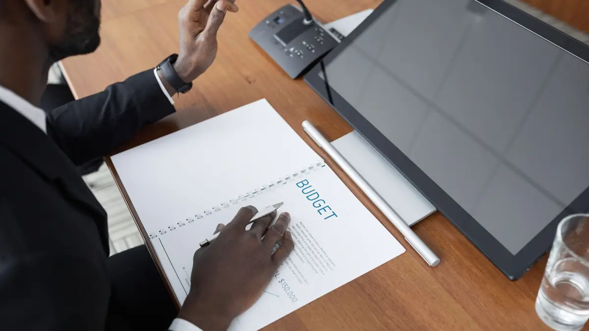 African American man in a meeting reviewing a budget document with a microphone