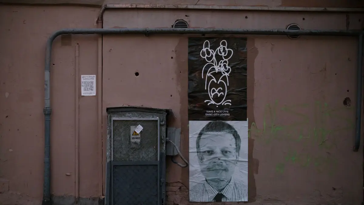 Street art and posters on a grungy urban wall, showcasing city life themes.