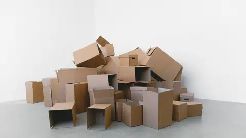 Pile of cardboard containers prepared for relocation on floor at home in daylight on white background