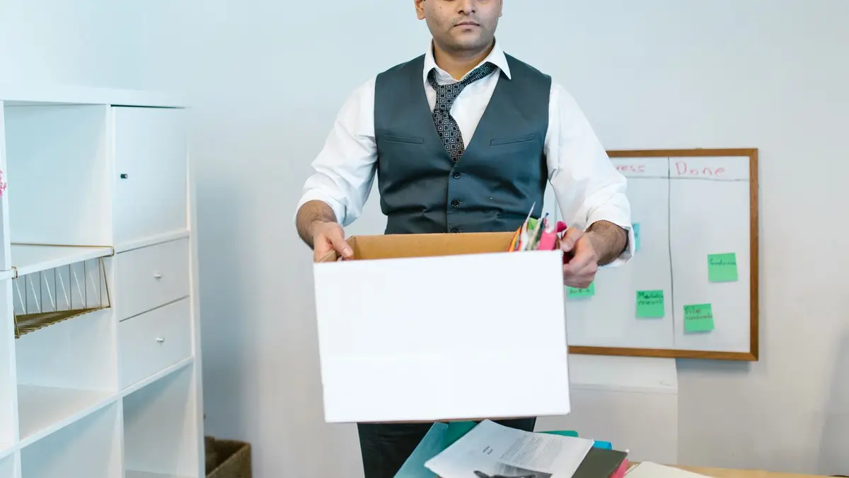 Professional man organizing office belongings in a cardboard box, preparing for transition.