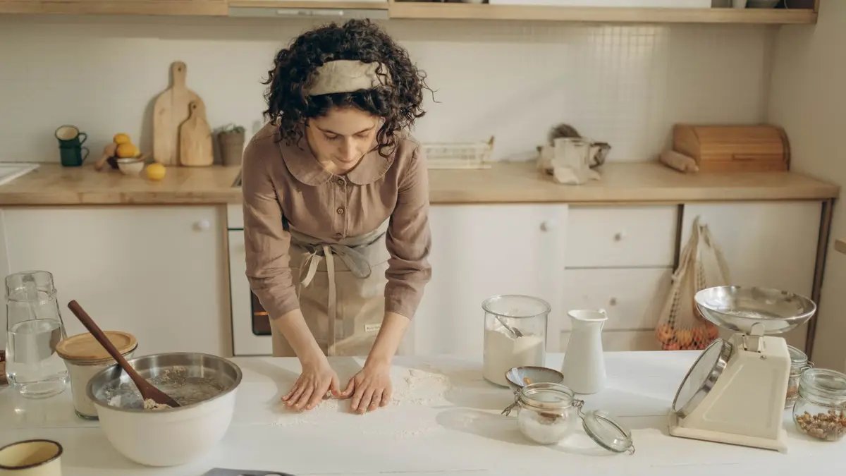 A woman preparing dough in a cozy kitchen setting with various baking tools.