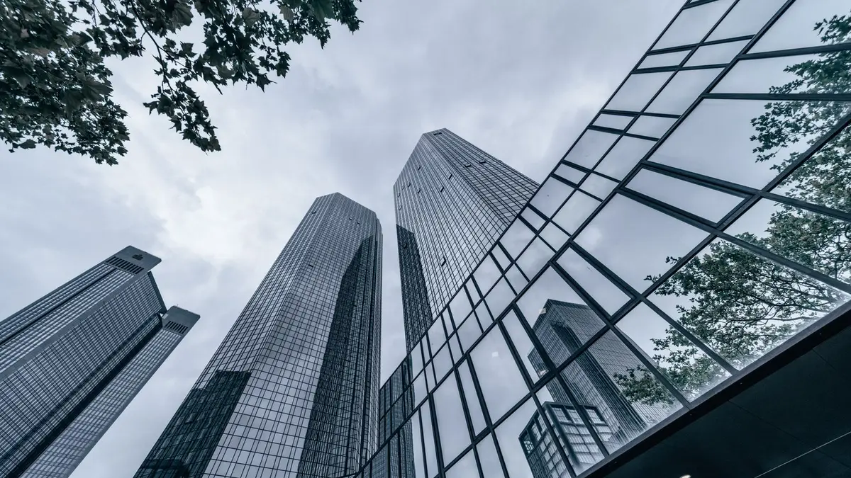 Modern skyscrapers with glass facades reflecting the urban skyline on an overcast day.