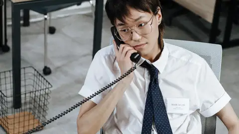 A focused customer service agent answering a phone call in an office setting.