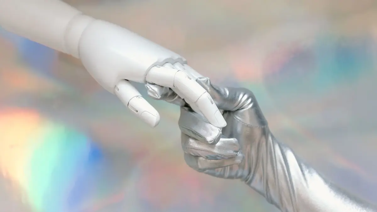 Close-up of a robot hand and silver-gloved hand touching, symbolizing human-robot connection.